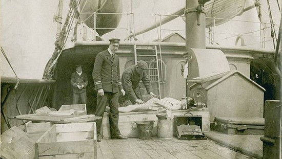 Body of RMS Titanic victim aboard rescue vessel CS Minia being made ready for makhift coffin. 1912